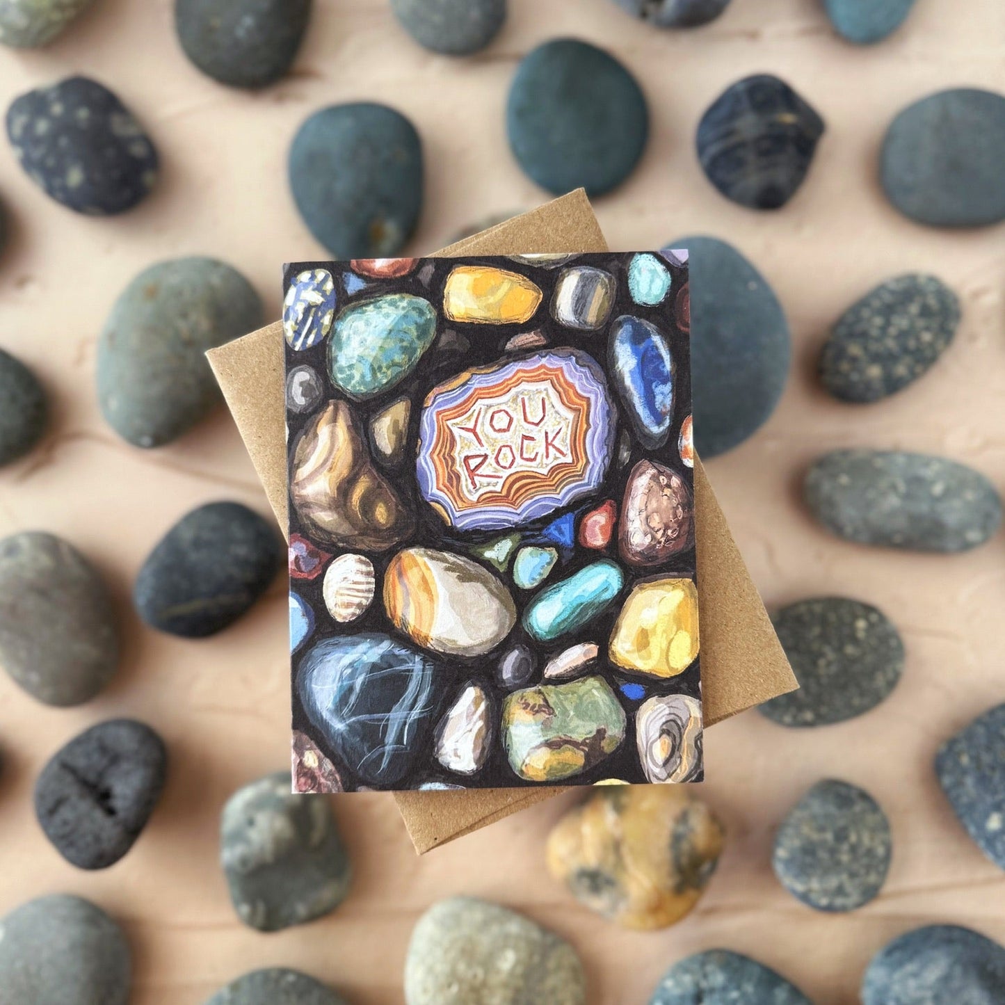 Greeting card with a 'You Rock' design on a bed of small rocks.