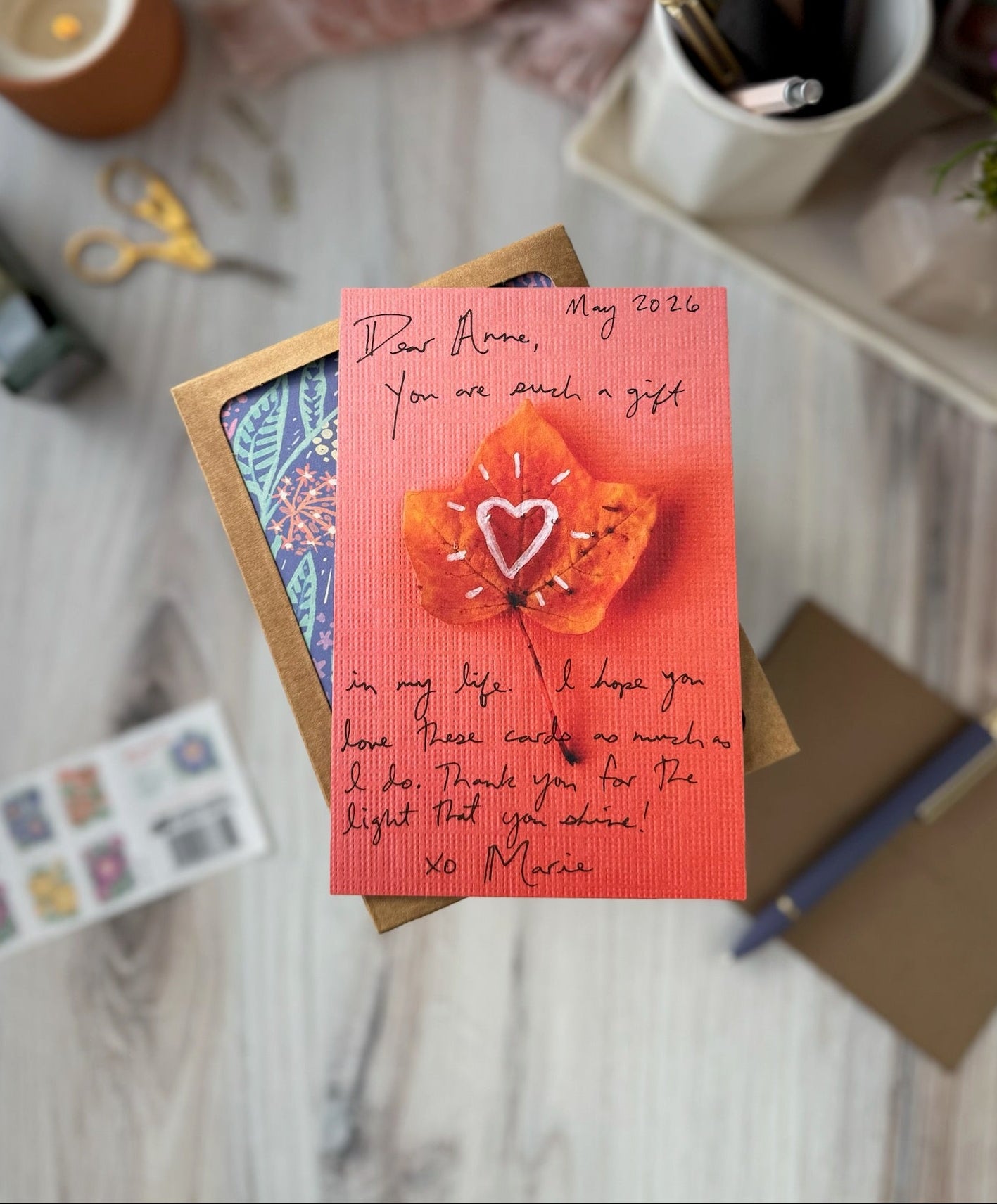 Greeting card with floral design and text on a table with stationery items.