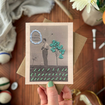 Hand holding a greeting card with decorative elements on a wooden surface.