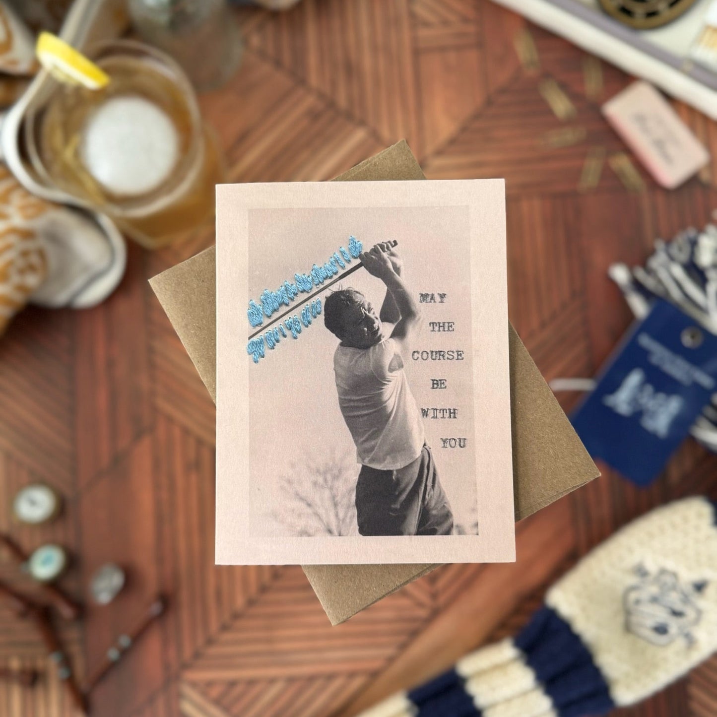 Greeting card with golf-themed design on a wooden table with golf accessories.