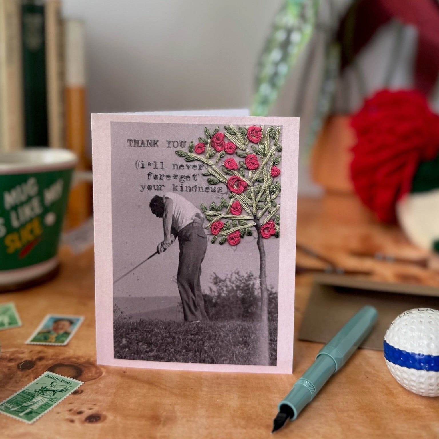 Greeting card with a golf-themed design on a desk with stationery items.
