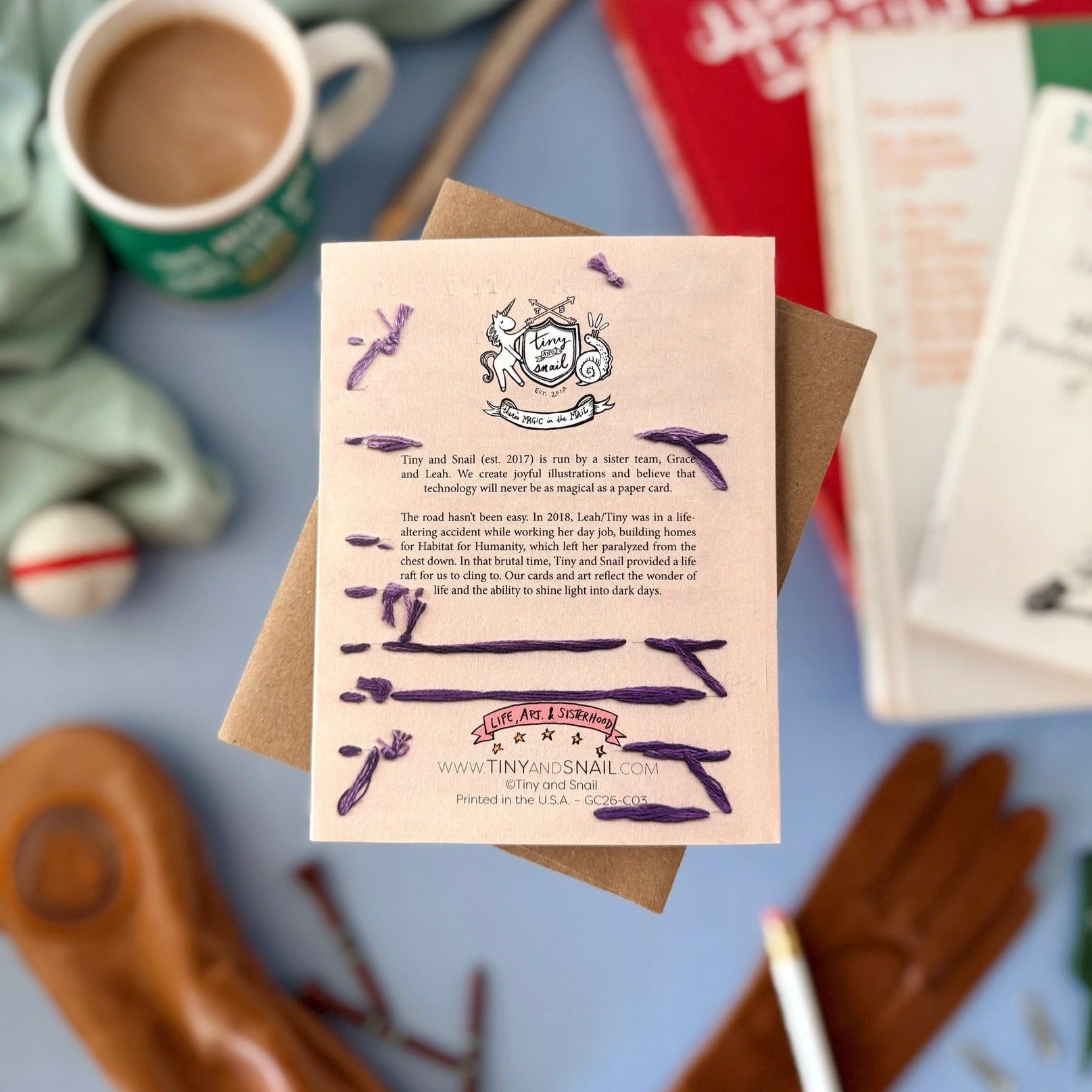 Card with text and illustrations on a table with a mug and books