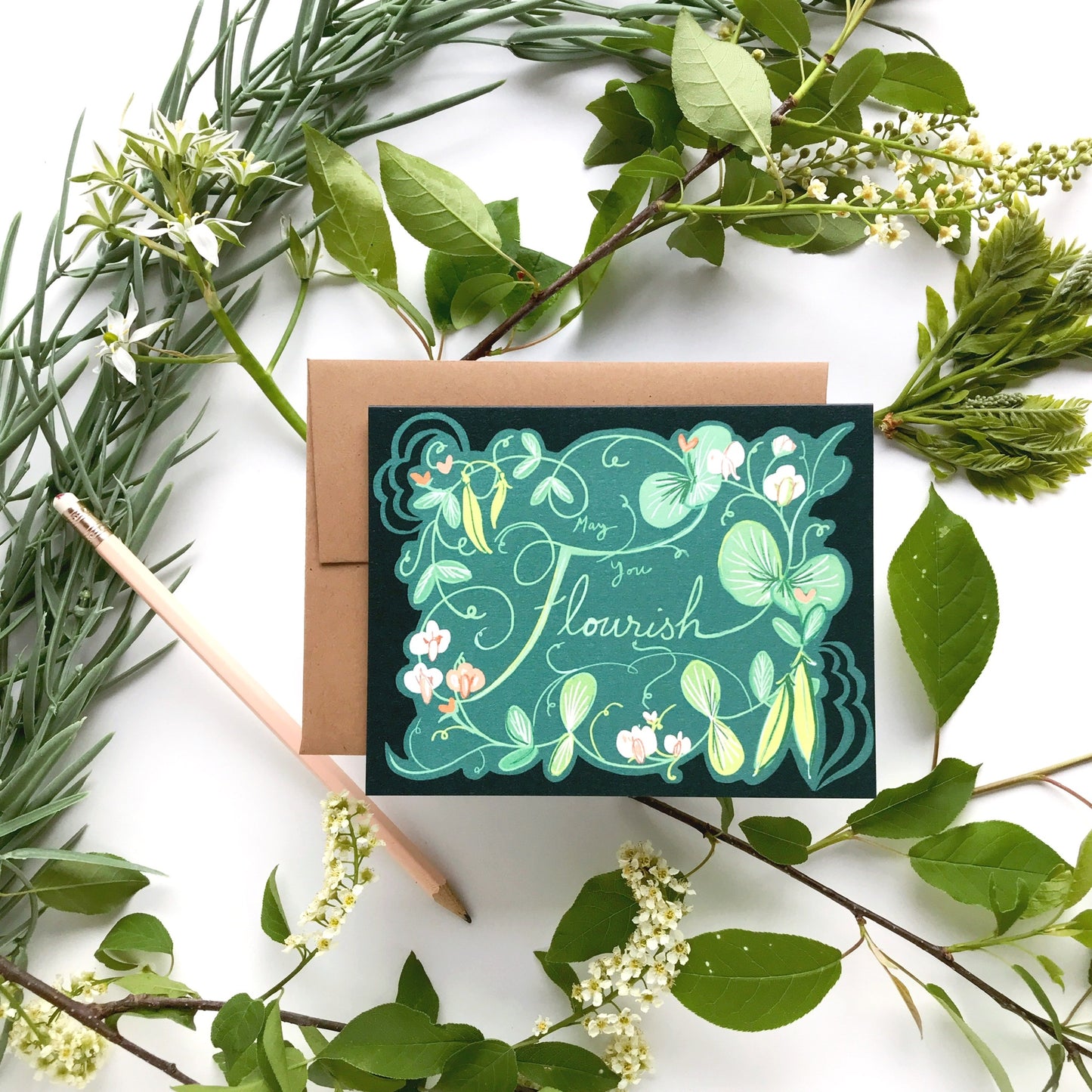 Greeting card that says "May you flourish" with floral design surrounded by greenery on a white background