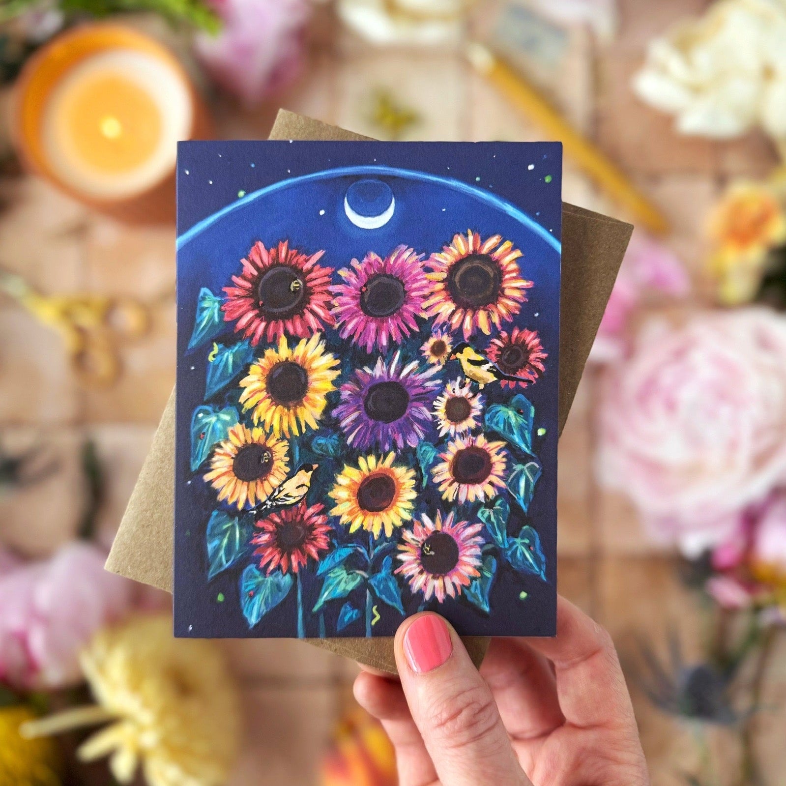 Hand holding a colorful sunflower card with the moon above